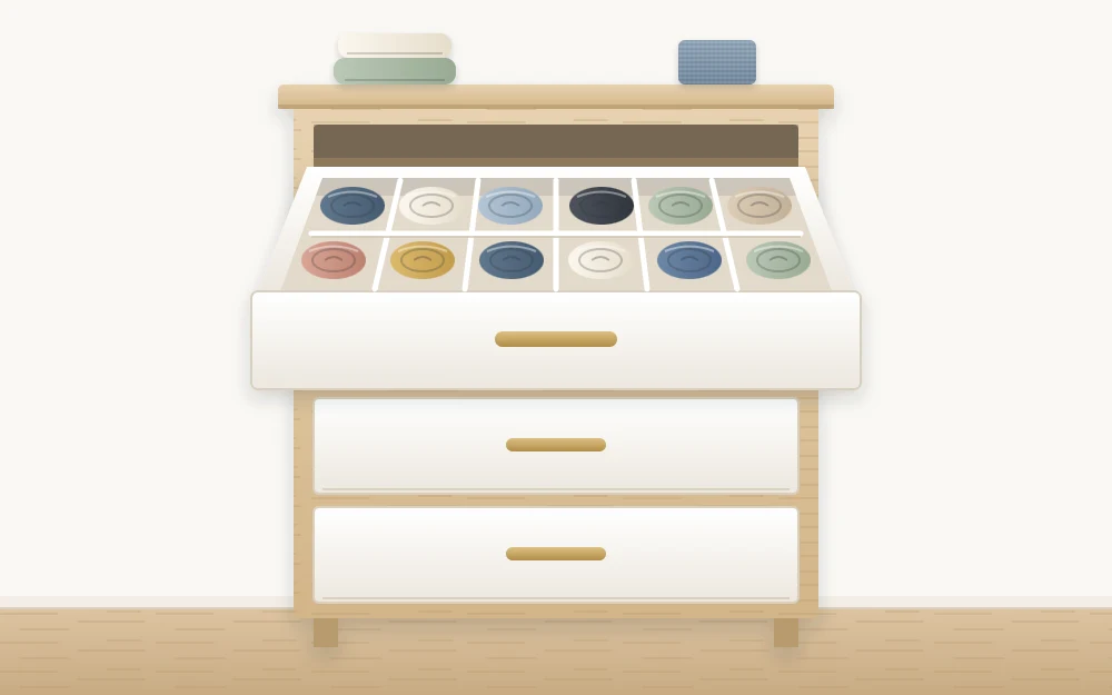 A three-drawer dresser from the front, the top drawer open to show compartments of rolled socks, the lower drawers closed