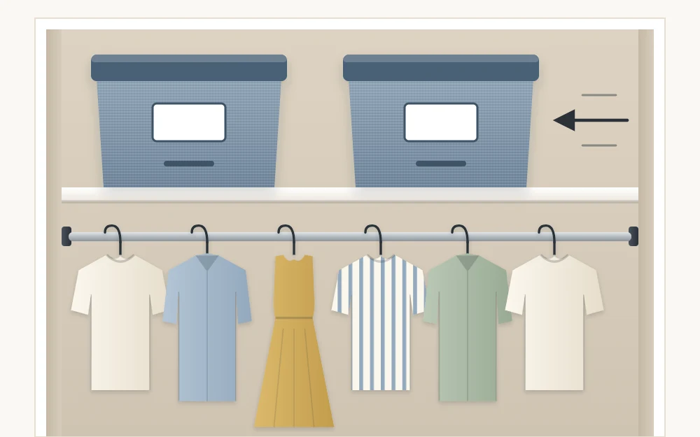 A lidded storage bin with a blank label being slid onto a high closet shelf beside a matching bin, above a rod of light garments